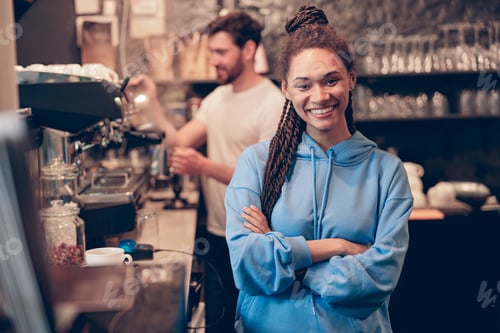 Preview: Beautiful young stylish woman barista standing at bar coffee machine and smiling. cafe worker.