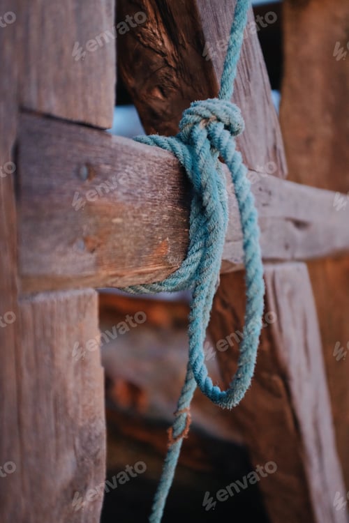 Preview: detail of a knot on a green rope tied around wooden timber