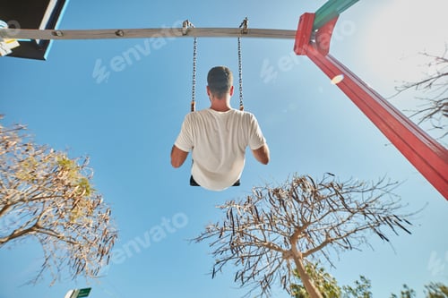 Preview: Man swinging on playground in sunlight