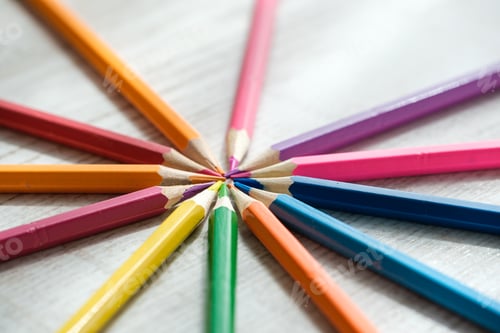 Preview: Coloured pencils arranged in a circle on a wooden background