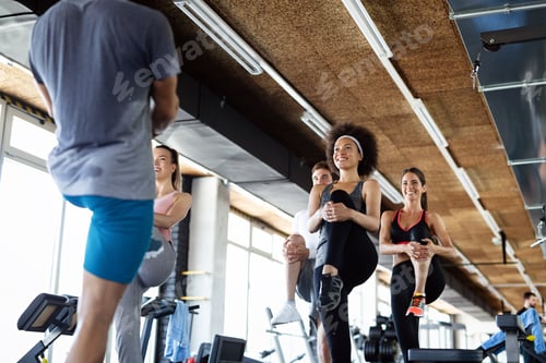 Preview: Group of fit people working out in a gym. Multiracial friends exercising together in fitness club.