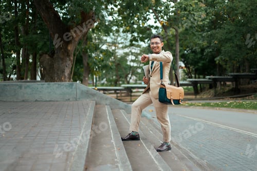 Preview: Smiling businessman checking wristwatch while commuting to office