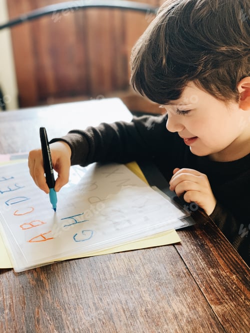 Preview: Young boy smiles and traces letters and learns his alphabet while homeschooling during a quarantine
