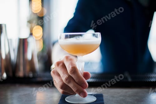Preview: Midsection of bartender serving glass of cocktail at bar