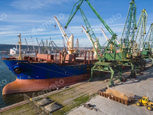 Preview: A bulk carrier ship loaded with grain is docked at a busy port, with workers and machinery seen in