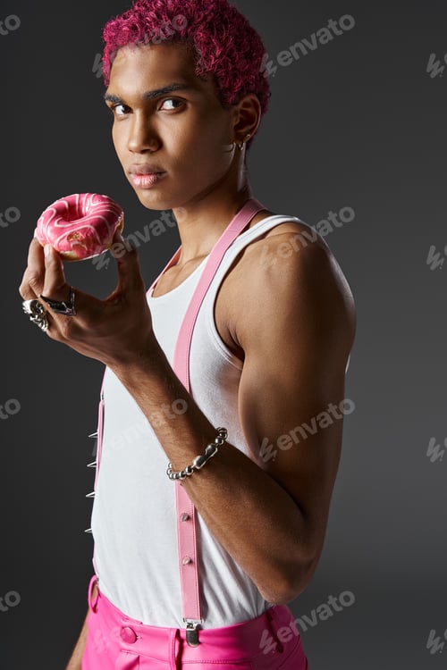 Preview: stylish man in pink pants and suspenders with accessories posing with donut, fashion and style