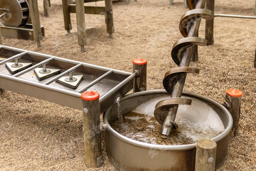 Preview: Children engage with interactive water play equipment featuring a spiral water screw