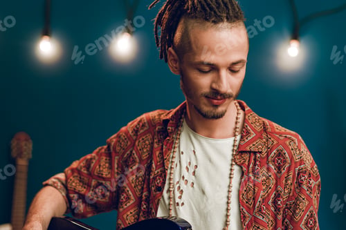 Preview: Young man guitar player sitting and performing on a couch