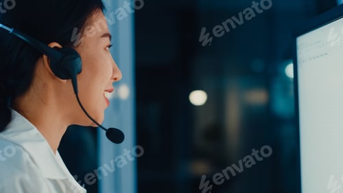 Preview: Millennial Asia young call center agent using computer and microphone headset working.