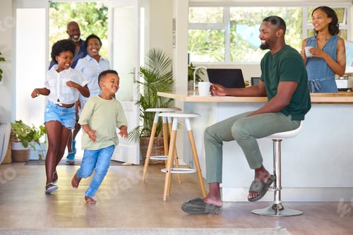 Preview: Grandparents With Grandchildren Returning Home To Parents Working On Laptop In Kitchen
