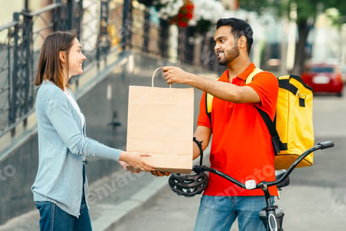 Preview: Excellent delivery to client in city. Smiling guy with backpack and bicycle gives paper bag to happy