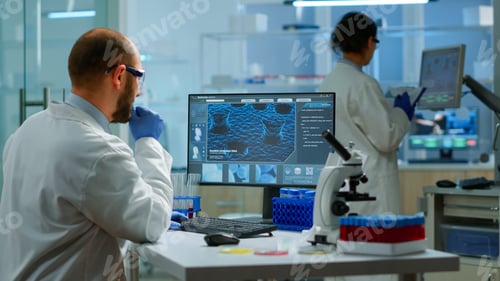 Preview: Man biologist checking DNA informations typing on pc