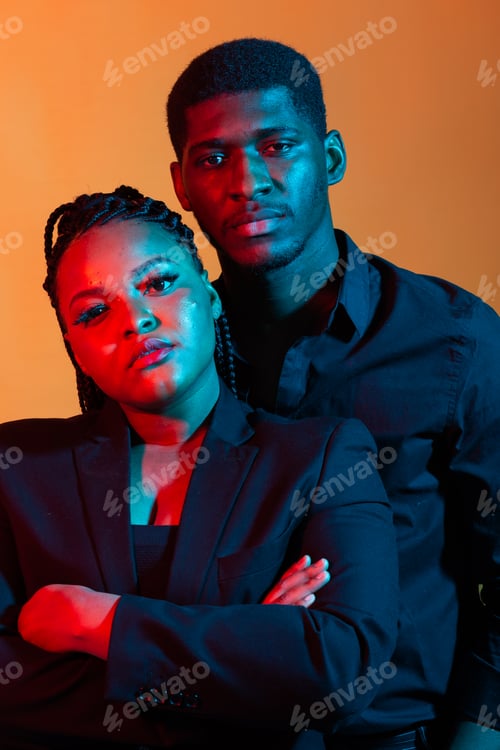 Preview: Portrait of young african american couple in love posing at studio dressed in classic clothes. Neon