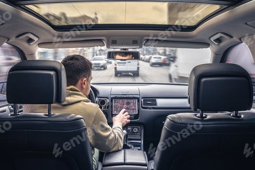 Preview: Man touching screen of a GPS navigation system in his car.