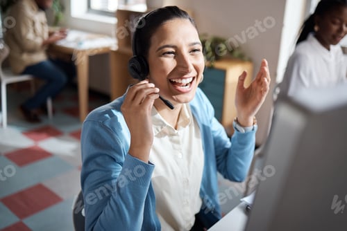 Preview: Shot of a young businesswoman using a headset and computer and looking excited in a modern office