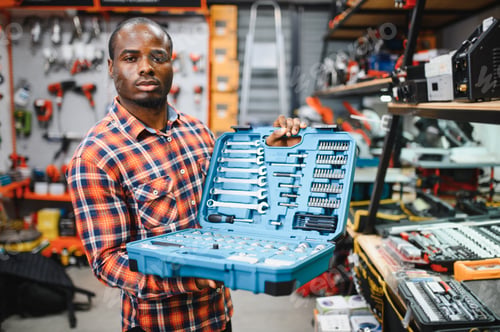 Preview: African american male buyer chooses a toolbox in a hardware store. A large selection of tools