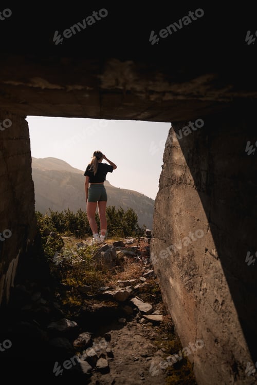 Preview: A hiker gazes out from a rugged concrete frame, capturing the beauty of the Pyrenean mountains