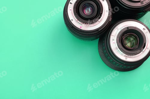 Preview: Several photographic lenses lie on a bright turquoise background. Copy space