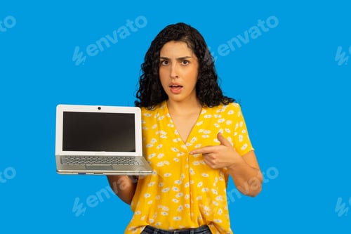 Preview: Young woman pointing at a blank laptop screen with a shocked face
