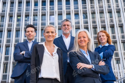 Preview: Group of confident business professionals posing in front of a modern building
