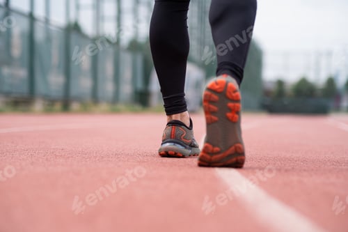 Preview: Closeup of runner legs in activewear, sprinting along the red rubberized track at an outdoor stadium