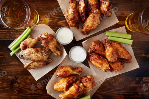 Preview: overhead view of four different flavored chicken wings with ranch dressing, beer, and celery sticks