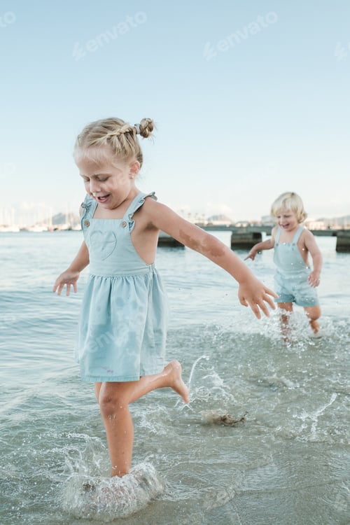 Preview: Cheerful cute children running in sea on coast in summer