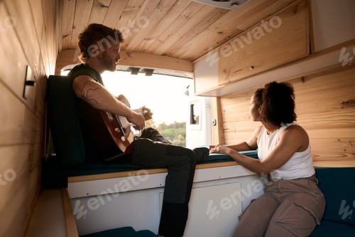 Preview: Musician playing guitar for girlfriend in camper van