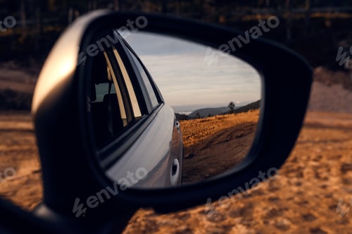 Preview: Driving in the car during sunset. Beautiful view of mountains and clouds in the rearview mirror