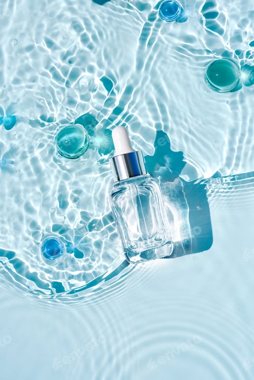 Vista previa: Mockup of cosmetic glass blue bottle with pipette and serum on water surface with waves