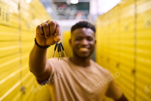 Preview: African American guy stands with keys at storage containers