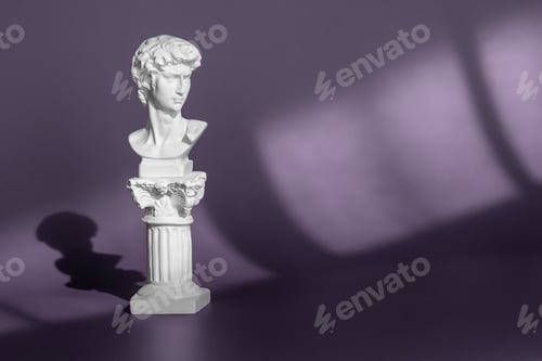 Preview: Gypsum copy of ancient statue head on purple background with light and shadow. White marble head of