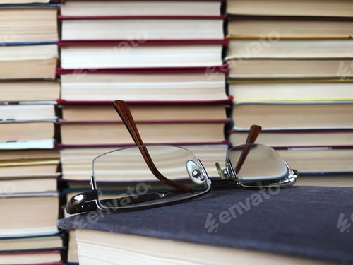 Preview: Glasses Rest on a Stack of Well-Loved Books