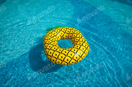 Preview: Yellow rubber ring floating in a blue pond on a summer day