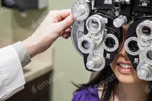 Preview: Ophthalmologist using a phoropter instrument to adjust an eyeglass perspection for a patient.