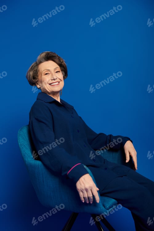 Preview: A beautiful woman in her 60s poses gracefully in stylish attire, exuding confidence and charm.