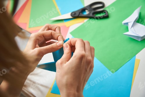 Preview: DIY concept. Woman make origami easter rabbit from color paper. Origami lessons