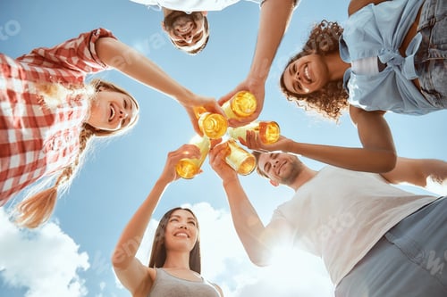 Preview: Happy young people are clinking bottles with beer and smiling
