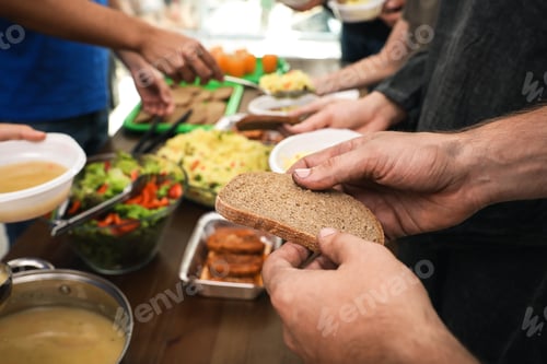 Preview: Poor man holding slice of bread at table in charity centre, closeup