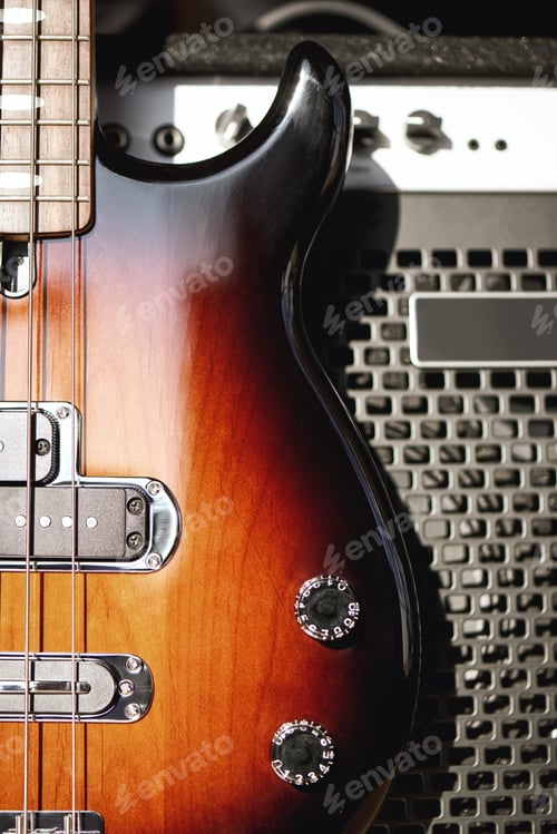 Preview: Playing guitar...Close up photo of a brown electric guitar with volume and tone control knobs and