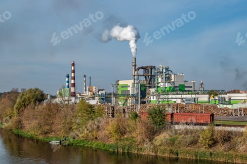 Preview: pipes of woodworking enterprise plant sawmill near river. Air pollution concept.