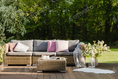 Preview: Cozy wooden terrace with grey sofa with pastel pink pillows and blanket
