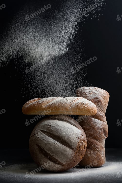 Preview: Freshly baked different bread on a black background, on which fl