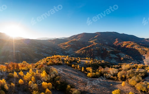 Preview: Sun rises above high mountain peaks with yellowed trees