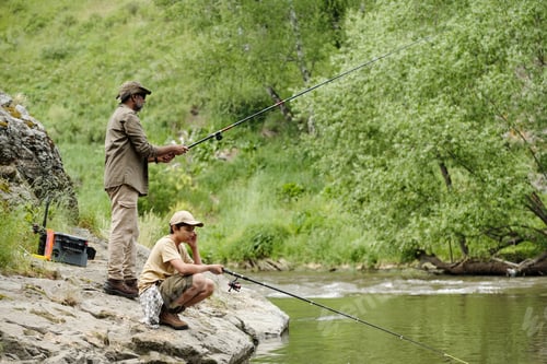 Preview: Middle Aged Man and Child Boy Fishing Together by River Outdoors