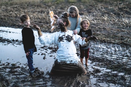 Preview: Happy woman and three children having fun on muddy field