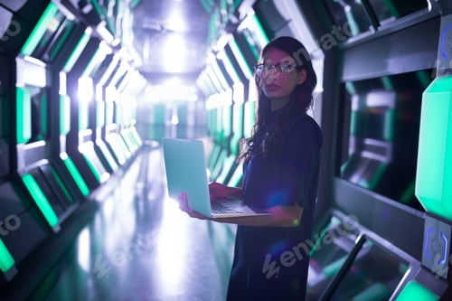 Preview: Woman using laptop in futuristic corridor, focusing on technology and innovation, copy space