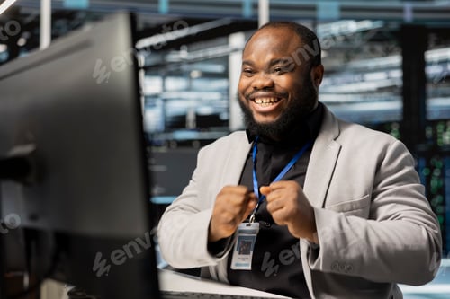 Preview: Smiling system administrator in data center pleased by stable performance