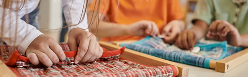 Preview: partial view of child playing with cloth and buttons in montessori school, banner