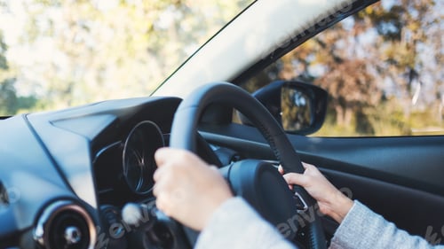 Preview: Closeup image of a woman holding steering wheel while driving a car on the road